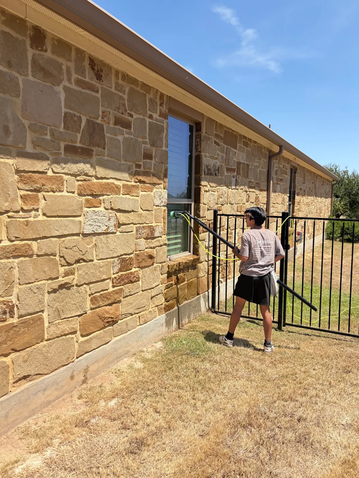 Cleaning windows on a stone ranch house